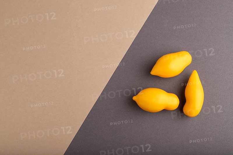Yellow tomatoes on beige and gray pastel paper background. Top view, copy space, flat lay. healthy food, vegetable, minimalism