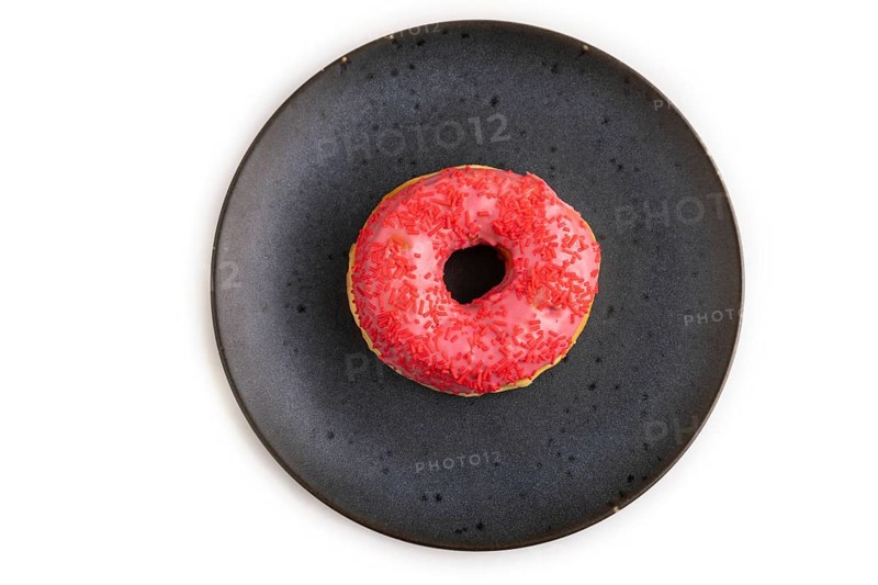 Pink Donut with sprinkles on blue ceramic plate isolated on white background, top view, flat lay, close up, minimalism