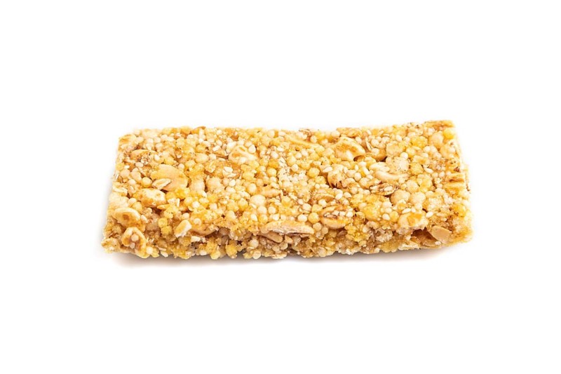 Granola bar with, caramel, nuts, flakes isolated on white background. Side view, close up