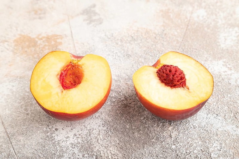 Peach Cut in half on brown concrete background. Side view, close up. healthy food, vegetable, minimalism