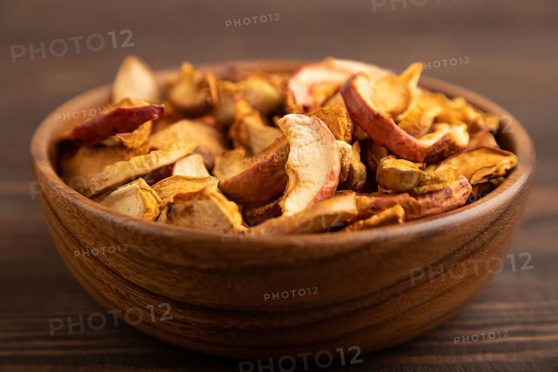 Dried Apples in wooden bowl on brown wooden background. Side view, close up, healthy food, minimalism. sweet, selective focus