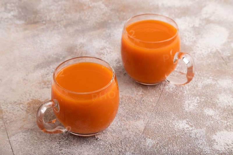 Two glasses with carrot juice, on brown concrete background. Diet, healthy eating concept. side view, close up, minimalism