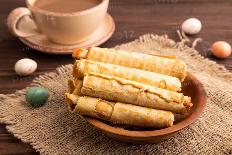 Waffles with caramel on brown wooden background and linen textile, cup of coffee, side view