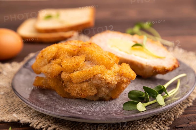 Chicken Schnitzel on gray plate with microgreen on brown wooden background and linen textile. side view, close up, selective focus