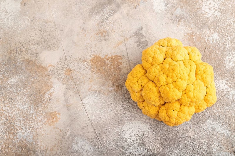 Yellow Cauliflower on brown concrete background. Top view, copy space, flat lay. healthy food, vegetable, minimalism