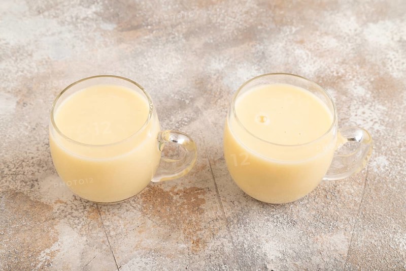 Organic non dairy banana and soy milk in glass on brown concrete background. Vegan healthy food concept, side view, close up