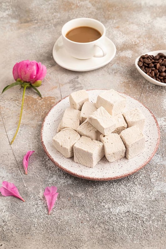 Coffee marshmallow with cup of coffee on brown concrete background. side view, close up