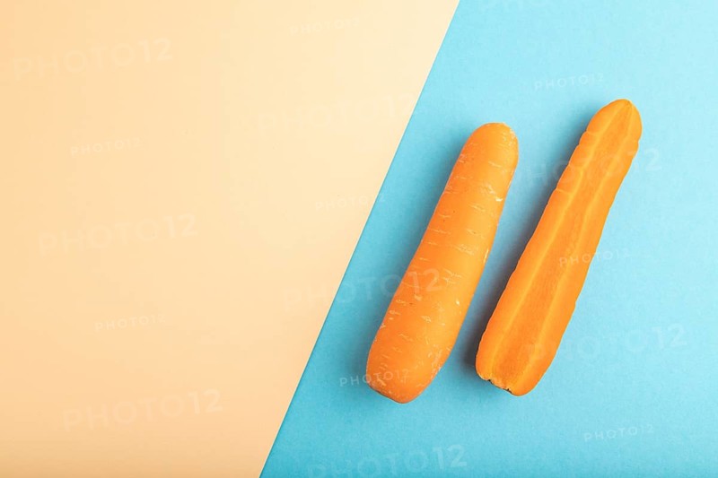 Orange Carrot on orange and blue pastel paper background. Top view, copy space, flat lay. healthy food, vegetable, minimalism