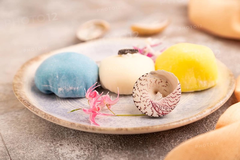 Japanese Mochi Cakes on brown concrete background and orange textile, side view, close up, selective focus