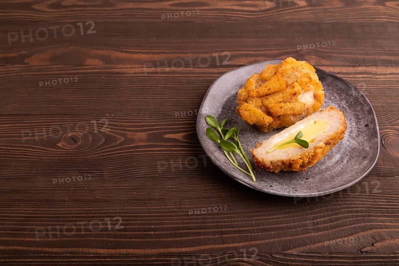 Chicken Schnitzel on gray plate with microgreen on brown wooden background. side view, copy space