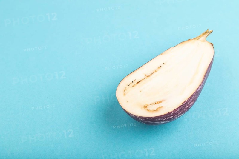 Purple Cutted eggplant with white stripes on blue pastel background. Side view, copy space. Tropical, healthy food, vegetable, slice, minimalism