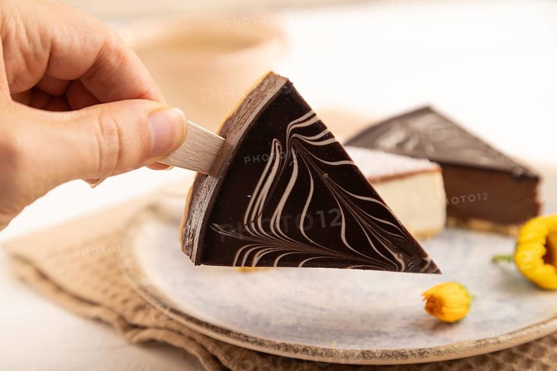 Chocolate and Vanilla Cake pops Marshmallow with hand with cup of coffee on white wooden background and beige linen textile. side view, close up, selective focus hold