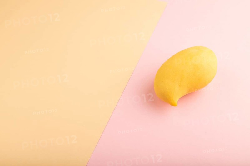 Orange mango on orange and pink paper pastel background. Side view, copy space. healthy food, minimalism