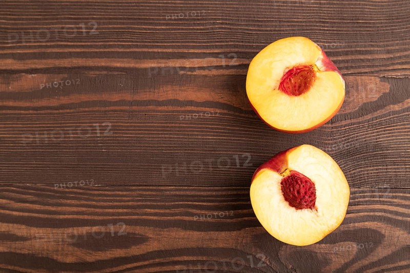 Peach Cut in half on brown wooden background. Top view, flat lay, copy space. healthy food, vegetable, minimalism