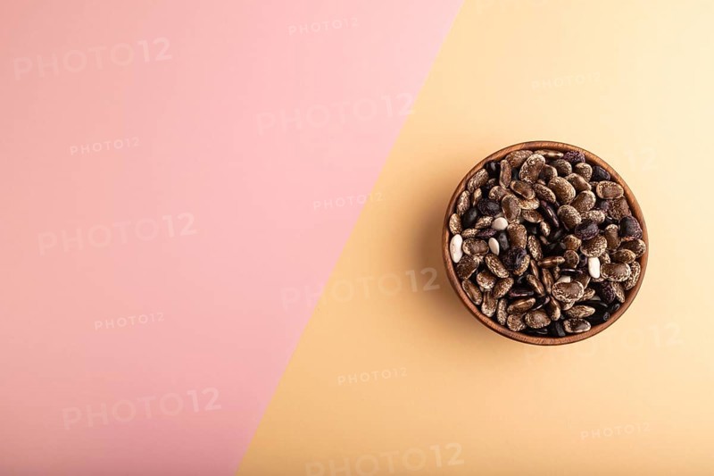 Wooden bowl with Kidney beans on pink and orange pastel paper background, top view, flat lay, copy space, minimalism