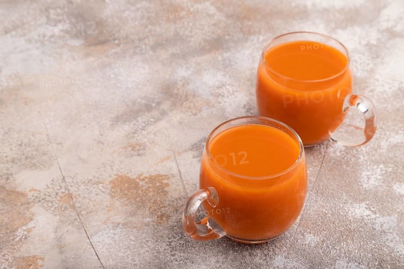 Two glasses with carrot juice, on brown concrete background. Diet, healthy eating concept. side view, copy space, minimalism