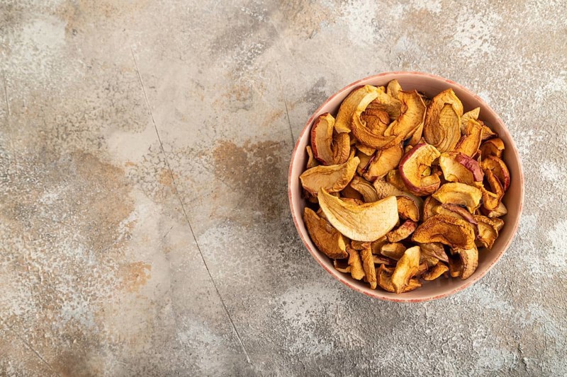 Dried Apples in ceramic bowl on brown concrete background. Top view, copy space, flat lay. healthy food, minimalism. sweet
