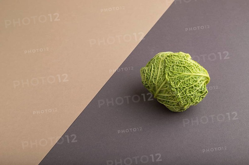 Green lettuce on beige and gray pastel paper background. Side view, copy space, flat lay. healthy food, vegetable, minimalism