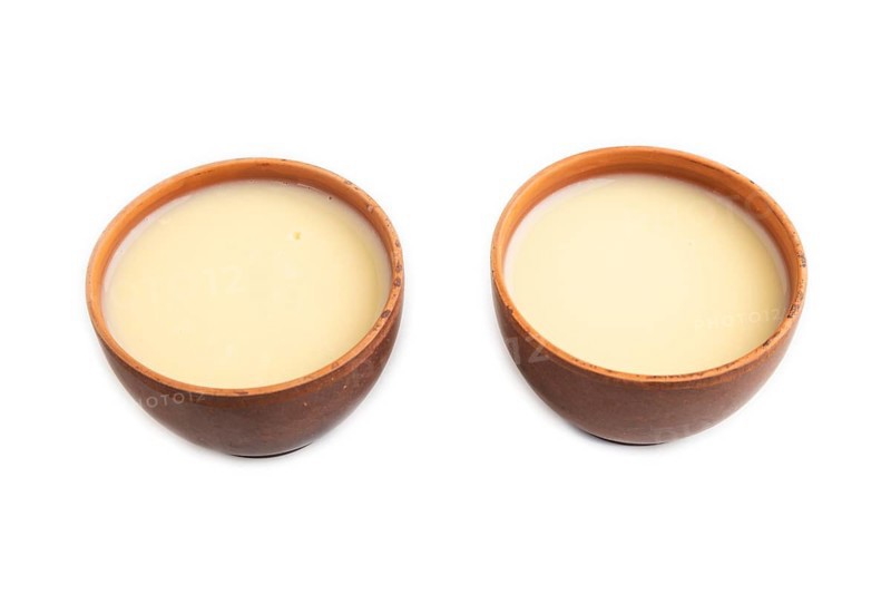 Organic non dairy banana and soy milk in clay cup isolated on white background. Vegan healthy food concept, side view, close up