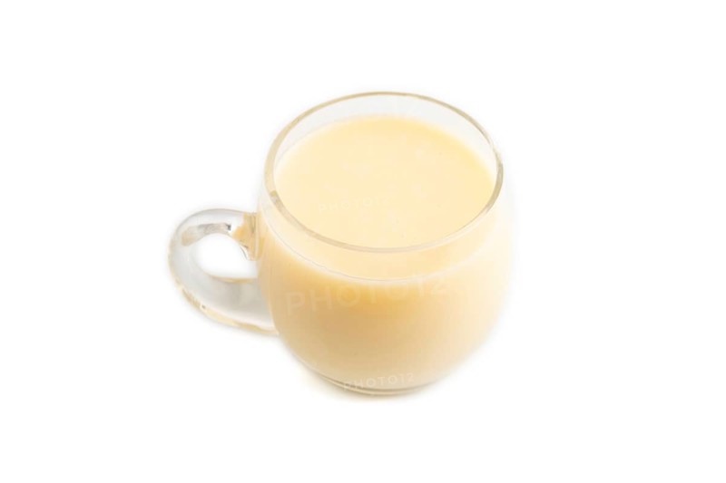 Organic non dairy banana and soy milk in glass isolated on white background. Vegan healthy food concept, flat lay, side view, close up