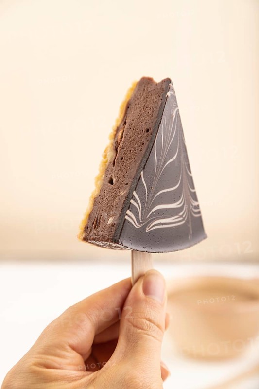 Chocolate and Vanilla Cake pops Marshmallow with hand with cup of coffee on white wooden background and beige linen textile. side view, close up, selective focus hold