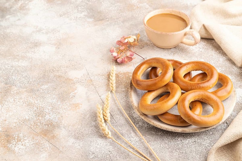 Homemade Ring Bagel with cup of coffee on brown concrete background and linen textile. side view, copy space