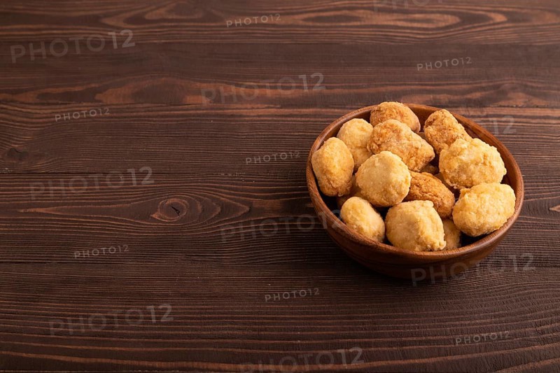 Fried crispy Chicken Nuggets on brown wooden background. side view, copy space