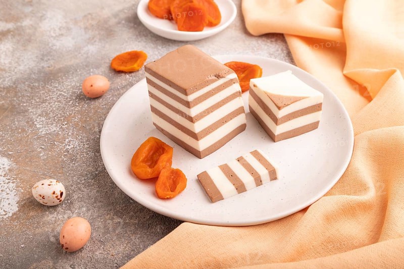 Cocoa and milk jelly with dried apricots on brown concrete background and orange textile, side view, close up, minimalism