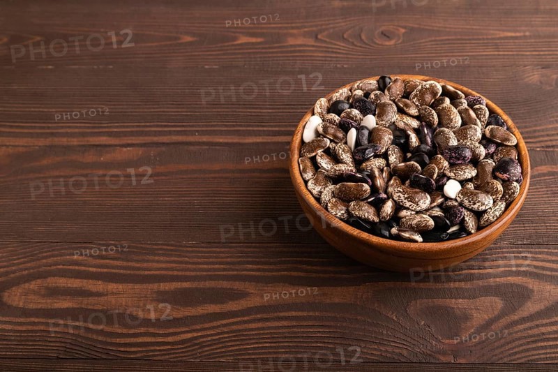Wooden bowl with Kidney beans on brown wooden background, side view, copy space, minimalism