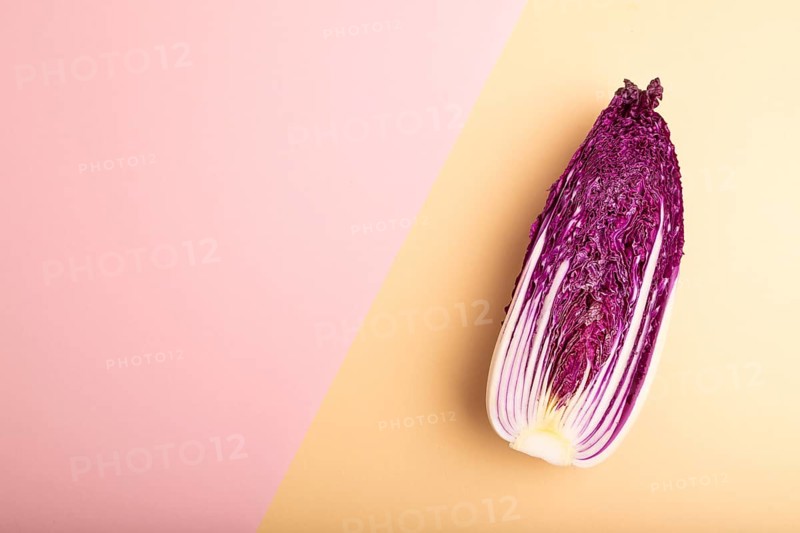 Purple Chinese cabbage on pink and orange pastel paper background, top view, flat lay, copy space, minimalism