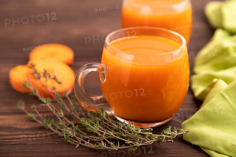 Two glasses with carrot juice, on wooden background and green textile. Diet, healthy eating concept. side view, close up, minimalism, selective focus
