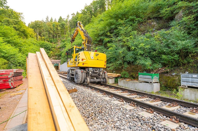 Baufahrzeug mit Kran auf Schienen in einer bewaldeten Baustelle, Bau der Hermann Hessenahn, Calw, Schwarzwald, Deutschland