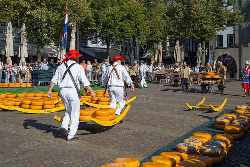 Männer in roten Hüten tragen Käseräder auf einem traditionellen Marktplatz mit vielen Besuchern, Käseträger, Käse, Käsemarkt, Alkmaar, Alkmar, Noord-Holland, Nordholland, Niederlande