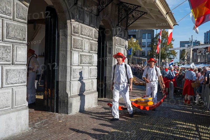 Männer mit Käse laufen durch ein historisches Marktgelände mit Publikum, ehemalige Stadtwaage, Käseträger, Käse, Käsemarkt, Alkmaar, Alkmar, Noord-Holland, Nordholland, Niederlande