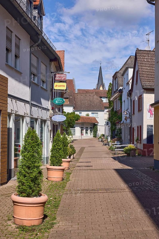 Fußgängerzone, Gebäude, allgemeine Architektur, Einzelhandelsgeschäfte, Zigarrenhaus Knöss, House of Smoke, Schuhmode Benner, Nasenschilder, einkaufen, Lottogeschäft, Schuhgeschäft, Tabakgeschäft, Blumenkübel, Kirchturm der Evangelischen Johanneskirche, blauer Himmel, Cumuluswolken, Kurhausstraße, Hofheim am Taunus, Main-Taunus-Kreis, Hessen, Deutschland