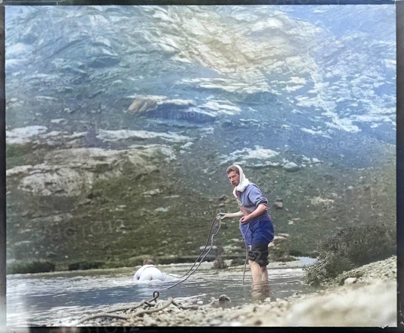 Person crawling across river stream secured by man holding a rope mountain exploration c 1900 possibly Cuillin mountains, Skye, Scotland, UK colourised image