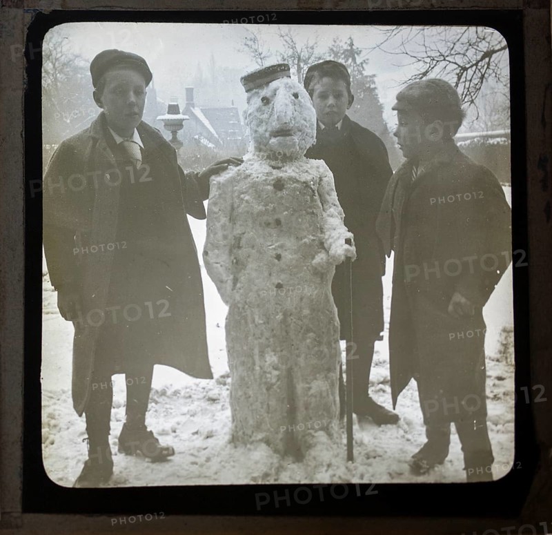 Magic lantern slide three boys making a snowman in a garden, England, UK c 1900-1910