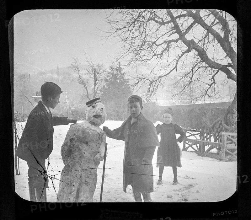Magic lantern slide c 1900-1910 of children making a snowman in garden
