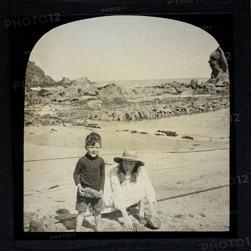 Magic lantern slide two children playing on a sandy beach circa 1900 location not known, presumed to be England, UK perhaps Cornwall