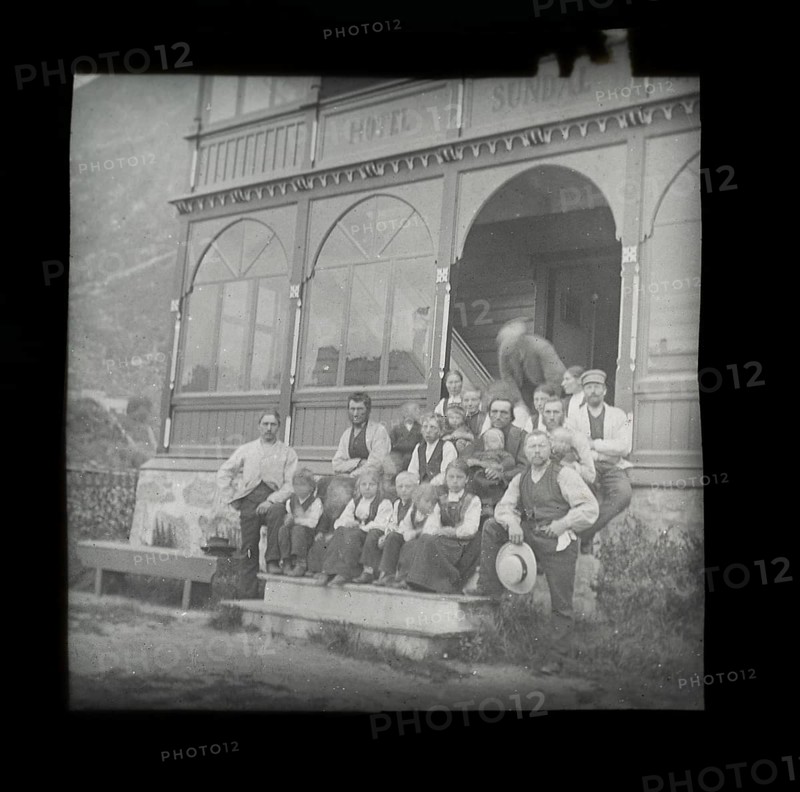 Magic lanterns slide group portrait of children and adults sitting on steps of Hotel Sundal, Sunndalsvegen, Mauranger, Hardanger, Norway, c 1900 now the Hardanger Fjord Lodge