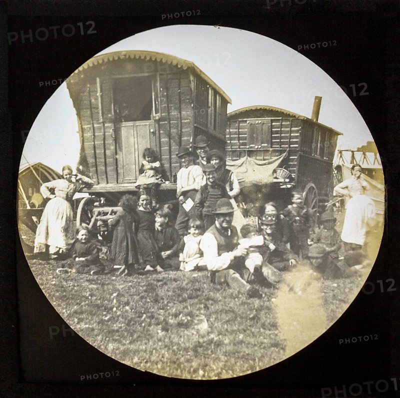 Magic lantern slide portrait of fairground travelling gypsy extended family and caravans, UK circa 1900