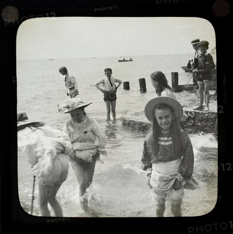 Magic lantern slide of children boys and girls paddling playing in the sea, UK circa 1900
