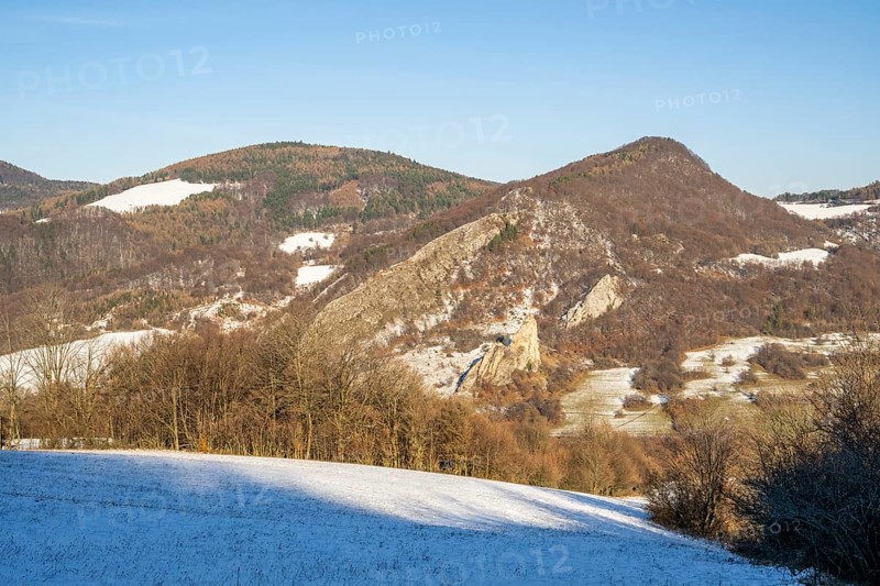 Cervenokamenské cliff (cervenokamenske bradlo), a huge rock at a mountain with bushes, trees and meadows in winter, Vápec, Horná Poruba, Slovakia