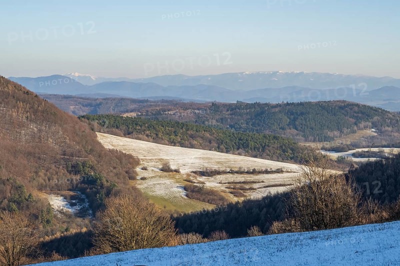 Typical valley with bushes, trees and meadows with the high tarta mountains in the background in winter, Vápec, Horná Poruba, Slovakia