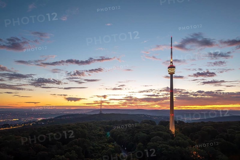 Illuminated television tower rises above forest in the morning red with clouds, Stuttgart-Degerloch, Baden-Württemberg, Germany