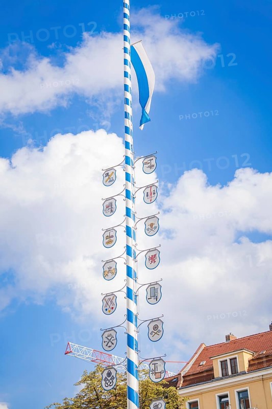 Bavarian maypole with coat of arms in front of blue sky and roof gable, Munich, Germany
