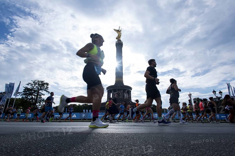 Runners run around the Victory Column against the backlight of the sun on the Great Star at the 51st BMW Berlin Marathon 2025 on 21 September 2025