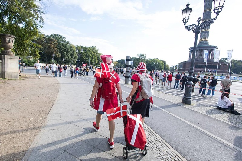 Two people carrying Danish flags run next to the Victory Column at the Großer Stern at the 51st BMW Berlin Marathon 2025 on 21 September 2025