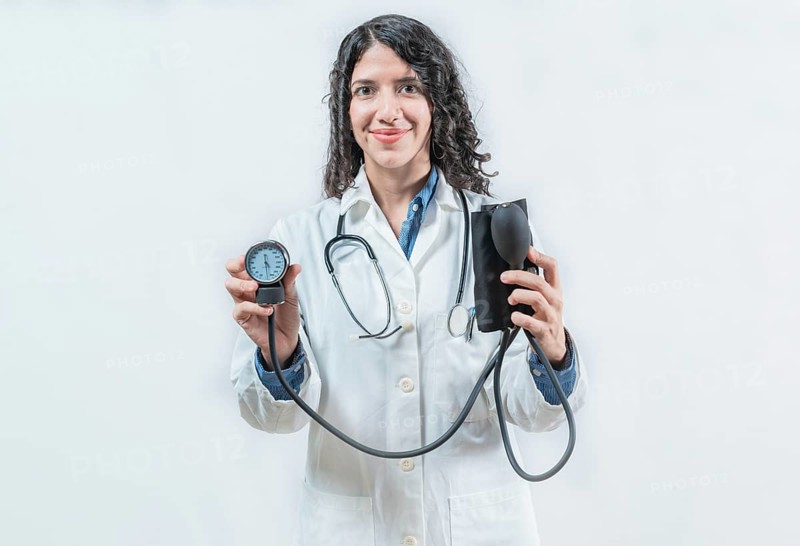 Smiling female doctor holding blood pressure monitor isolated. Female doctor showing tensiometer on isolated background