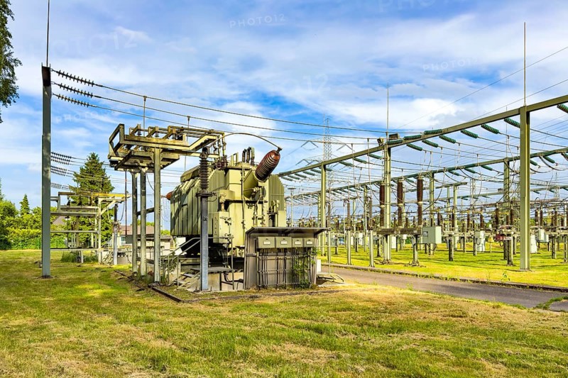 Left large transformer transformer transformer power transformer in substation, right hanging suspended power lines for transmission of electrical energy power supply, Germany